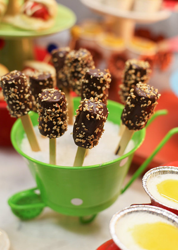 Pirulito de banana com chocolate e farofa de castanha de caju