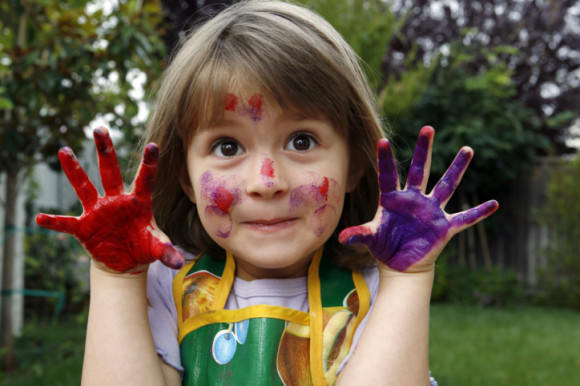 Close-up of a girl showing her hands painted with colors